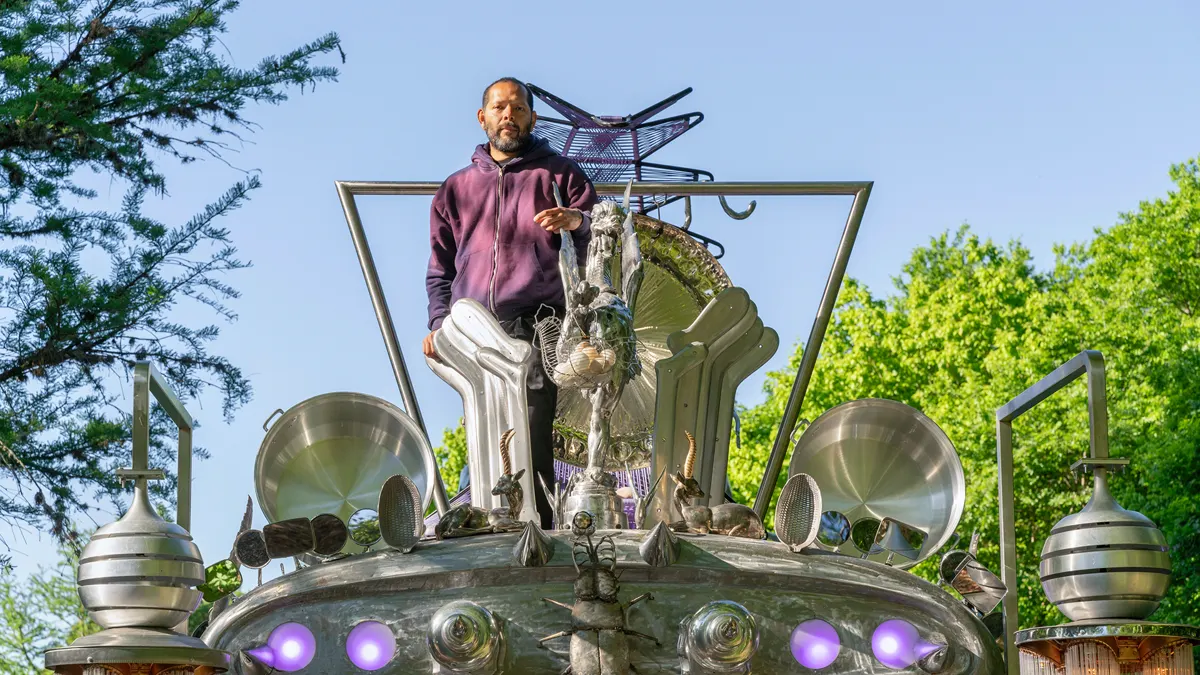 Guadalupe Maravilla stovi ant savo skulptūrinio autobuso „Mariposa Relámpago“, papuošto blizgiais metaliniais gongais, dubenimis ir violetinėmis lempomis