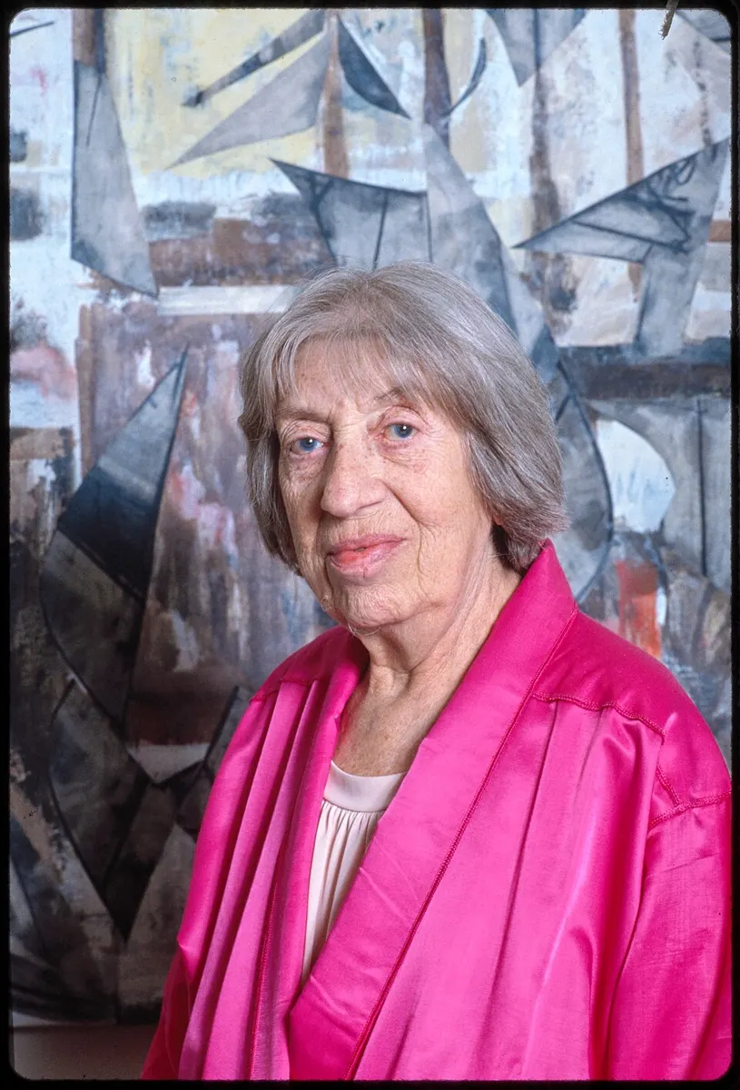 Lee Krasner 1983 m. prie savo abstraktaus paveikslo, ryškiai rožiniu švarku