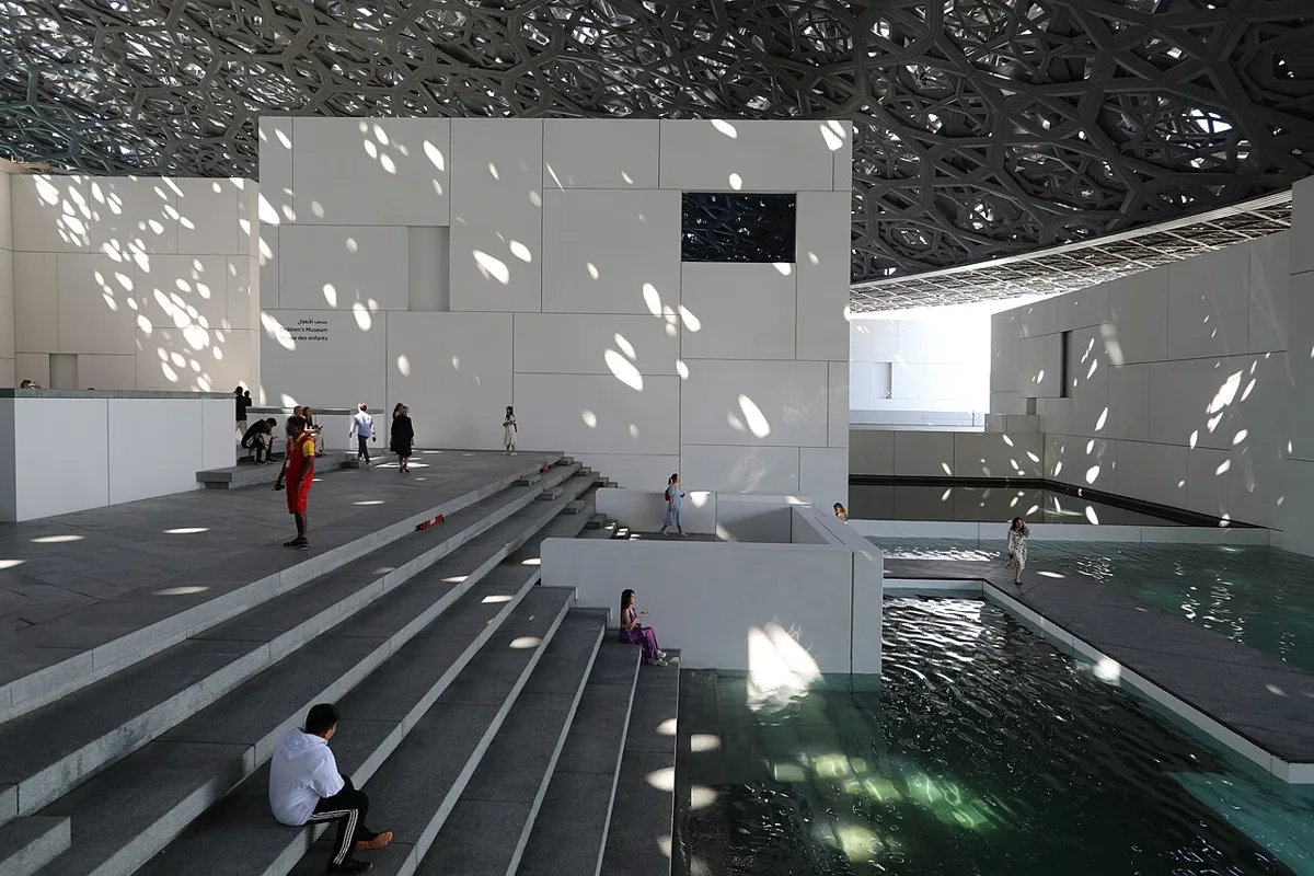 Louvre Abu Dhabi vidinis kiemas po Jeano Nouvelio kupolu: šviesos dėmės ant baltų sienų, laiptai ir vandens baseinai