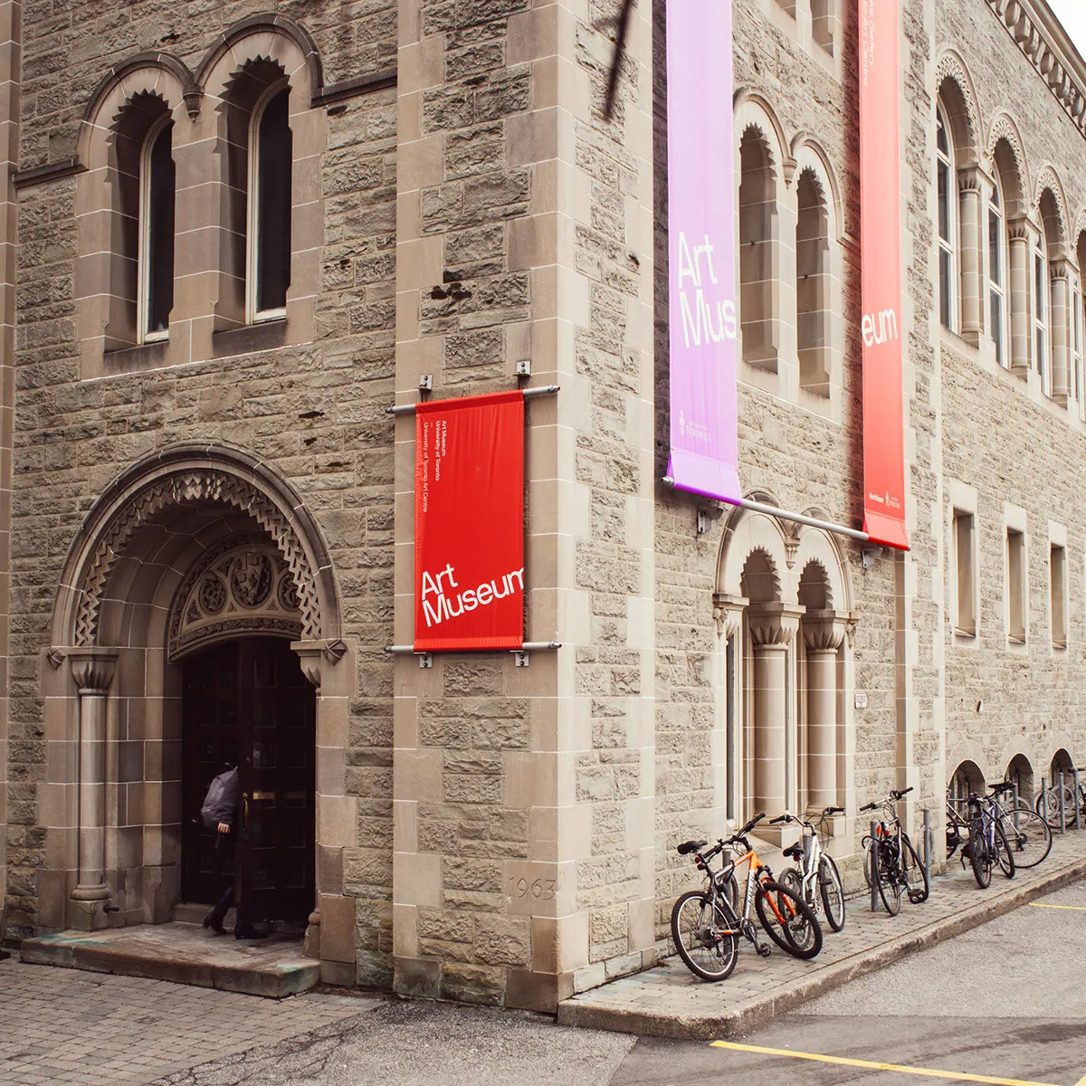Toronto universiteto meno muziejaus pastatas su raudonomis ir violetinėmis vėliavomis, pagrindinis bienalės centras